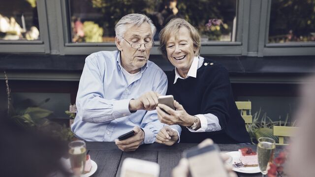Eldre par sjekker telefonen på kafe 